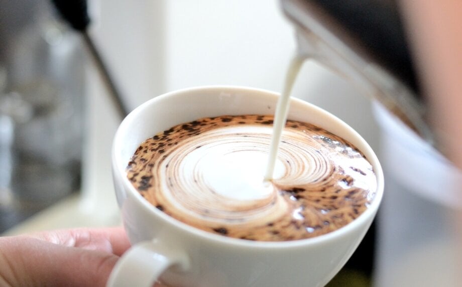 barista dekoruje kawę spienionym mlekiem