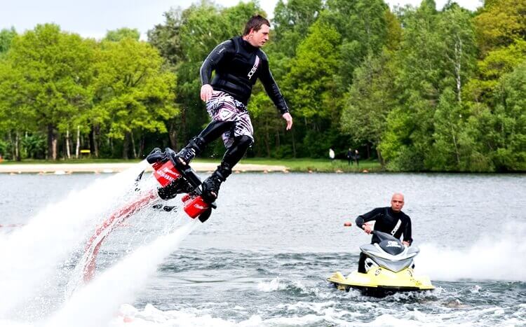 mężczyzna lata na flyboardzie nad jeziorem
