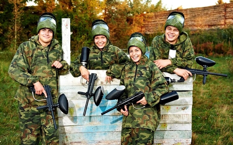 grupa przyjaciół pozuje w do zdjęcia w strojach do gry w paintball