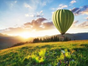 zielony balon na ogrzewane powietrze leci w górach na tle zachodu słońca