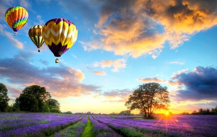 balony na ogrzewane powietrze lecące o zachodzie słońca nad wrzosowiskiem