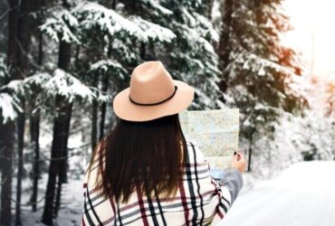 kobieta zimą w lesie trzyma w rękach mapę widok tyłem,