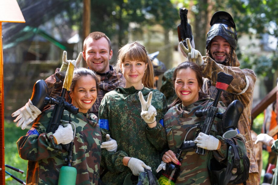 uśmiechnięci młodzi ludzie grający w paintball