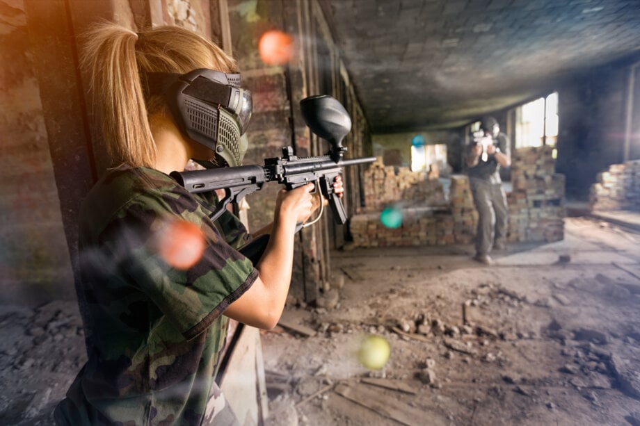 gracze w paintball strzelający do siebie