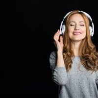 Zrelaksowana kobieta w słuchawkach, słuchająca muzyki
