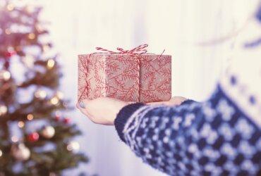 Kobieta trzymająca w rękach prezent na tle choinki świątecznej