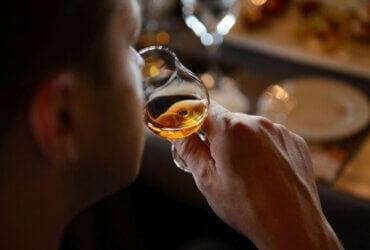Mężczyzna wąchający whisky w szklance