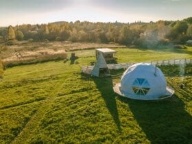 Widok z lotu ptaka na namioty glampingowe. Wokół las i zieleń.