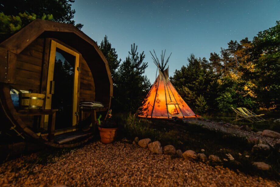 Drewniana sauna oraz rozświetlony od wewnątrz tipi.
