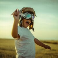 uśmiechnięty chłopiec w czapce pilotce i okularach
