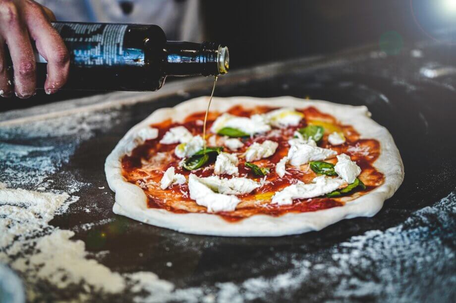 Przygotowanie pizzy z surowego ciasta, oliwy z oliwek, bazylii, mozzarelli, która ma być w piekarniku